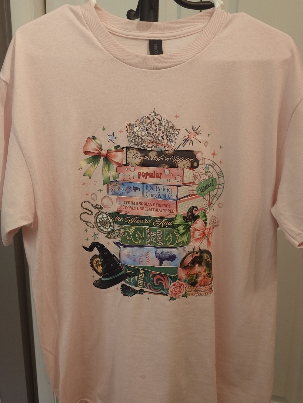 Wicked Themed Light Pink Graphic Tee with Colorful Book Stack Design Size LG